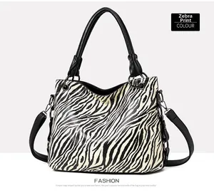 Detail of zebra print tote bag featuring black leather handles and silver metal hardware