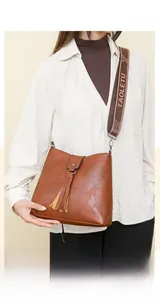 Détail d'un sac seau en cuir marron avec franges et bandoulière large brodée