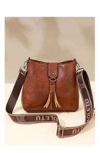 Gros plan du sac seau marron avec franges et large bandoulière à motifs personnalisés