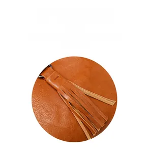 Gros plan d'un sac seau en cuir orange avec de longues franges et détails en métal
