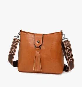 Gros plan du sac seau marron montrant la texture cuir grainé et détail gland