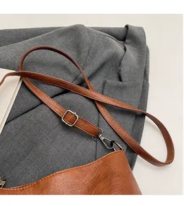 Detail of brown leather bucket bag with adjustable strap and textured pebble finish