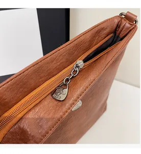 Detail of smooth metal zipper and leather texture on a brown vintage crossbody bag