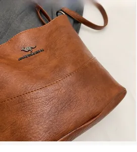 Close-up of brown litchi pattern PU leather bucket bag with metal kangaroo logo detail