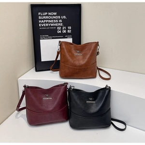 Detailed view of leather bucket bags in brown, burgundy, and black with kangaroo logo