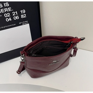 Detailed interior of wine red leather crossbody bag showing multiple zipper compartments