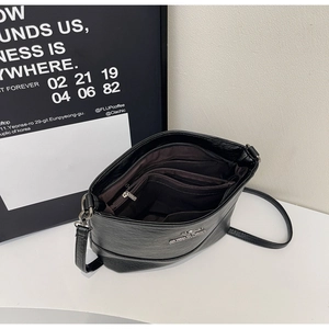 Detail view of black pebble leather crossbody bag with multiple inner compartments