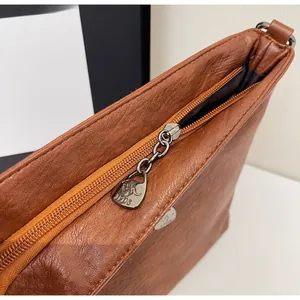 Detail of the brown lychee pattern leather bag featuring a kangaroo logo metal zipper