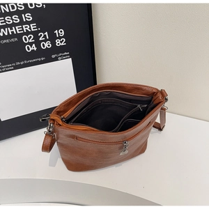 Detail of caramel faux leather crossbody bag showing internal multi-layered zipper pockets