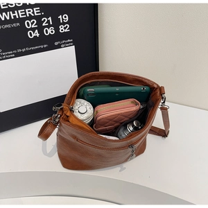 Detail showing spacious interior of caramel crossbody bag with tablet and daily essentials