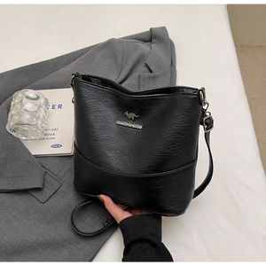 Close-up of black leather crossbody bag with silver kangaroo emblem and lychee texture