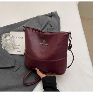 Close-up of burgundy textured leather bucket bag featuring metal kangaroo logo