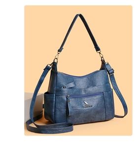 Detail view of navy blue leather handbag with multiple pockets and metal brand logo