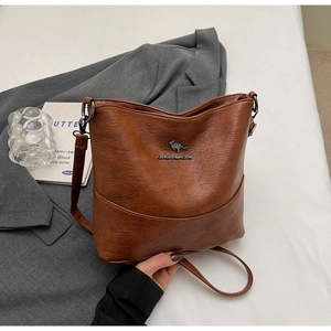 Close-up of brown vintage leather bucket bag with kangaroo logo on white bedding