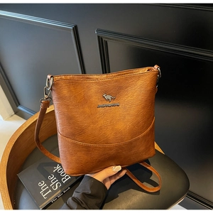 Detail of caramel brown faux leather bag with silver kangaroo logo on a leather chair
