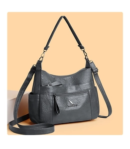 Detail view of the dark grey pebbled leather texture and metal logo on the handbag
