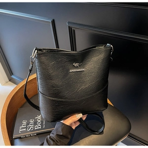 Detailed view of black pebbled leather bucket bag with silver kangaroo logo and strap