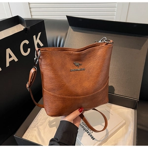 Unboxing detail of brown lychee leather crossbody bag with kangaroo logo and metal plaque