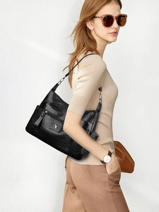 Detailed view of black litchi leather crossbody bag with kangaroo logo on model