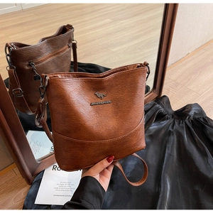 Detail of dark brown leather bucket bag featuring silver kangaroo logo and smooth texture