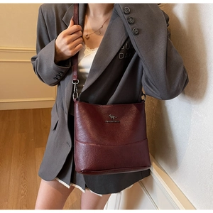 Close-up of deep wine red crossbody bag with textured leather and kangaroo logo