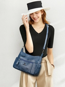 Detail view of the soft navy blue PU leather texture and kangaroo logo on the handbag