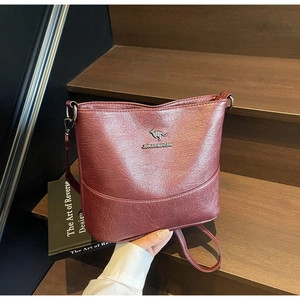 Detail of burgundy bucket bag featuring a kangaroo logo and premium pebble leather texture