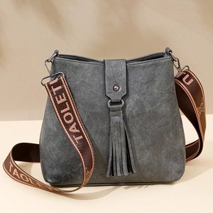 Sac seau minimaliste en cuir gris foncé avec pompon et bandoulière en jacquard