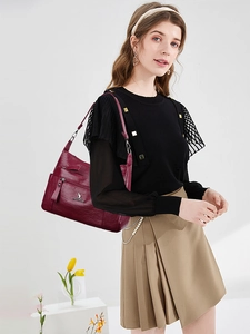 Detail view of burgundy leather shoulder bag with zipper pockets and silver kangaroo logo