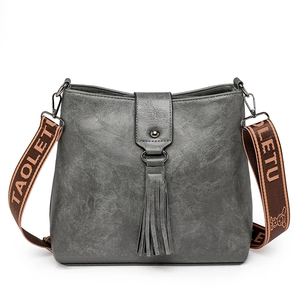 Sac seau gris minimaliste avec longues franges et large bandoulière en jacquard