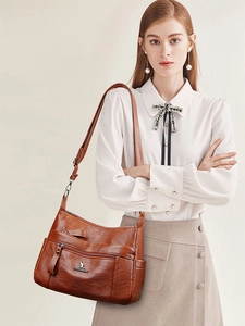 Detail of vintage brown leather shoulder bag with zipper pockets and silver kangaroo logo