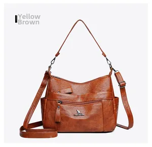 Close-up of yellow-brown leather crossbody bag with lychee texture and metal logo detail