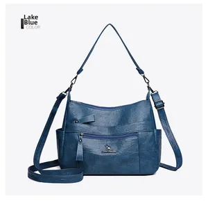 Close-up of lake blue leather crossbody bag with pleated texture and metal zippers