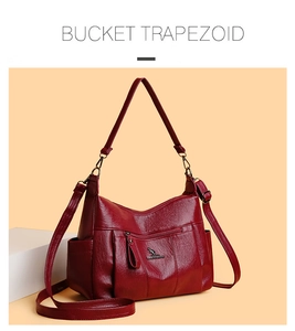 Detail of red leather bucket trapezoid bag with golden kangaroo logo and zip pocket