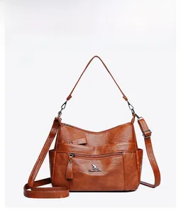 Close-up of the brown lychee-textured leather cross-body bag featuring a metal kangaroo logo