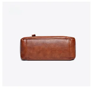 Detail view of the brown leather shoulder bag bottom featuring fine stitching and texture