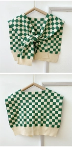 Close-up of green and beige checkered knit shawl showing ribbed edges and soft fabric