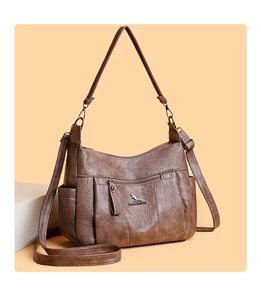 Close-up of brown textured leather shoulder bag showing zipper pockets and adjustable strap