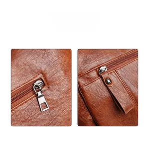 Detail view of brown leather bag showing dual zipper structure and fine grain texture