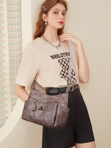 Detail of dark brown leather crossbody bag with kangaroo logo and multiple zippers