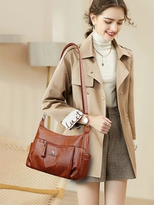 Detailed view of brown oil-wax leather shoulder bag with side pockets and metal brand logo