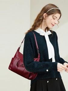 Detail view of burgundy faux leather crossbody bag with kangaroo logo and shoulder strap