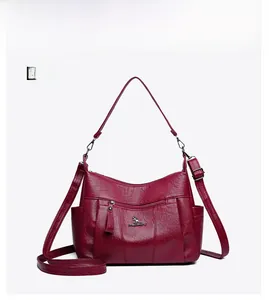 Detail view of wine red crossbody bag featuring textured lychee grain leather and zip pocket