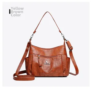 Detail view of yellow-brown leather crossbody bag with metallic logo and secure zippers
