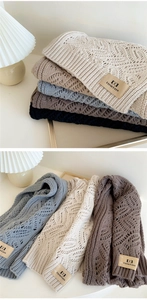 Detail of diamond hollow knit texture and brand leather label on multiple scarves
