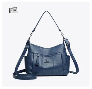 Detail view of lake blue leather crossbody bag with front zipper and metal kangaroo logo