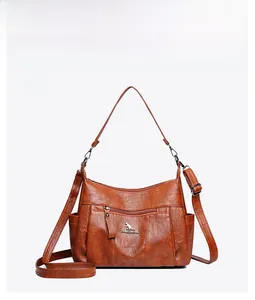 Detailed front view of a brown pebbled leather crossbody bag with golden kangaroo logo