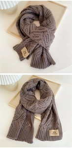 Detailed macro view of tan knit scarf with textured diamond patterns and brand label