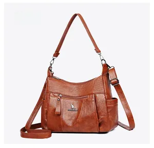 Macro side view of caramel brown crossbody bag with multi-pocket design and silver hardware