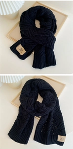 Close-up of thick black knit scarf with diamond texture and brand logo label